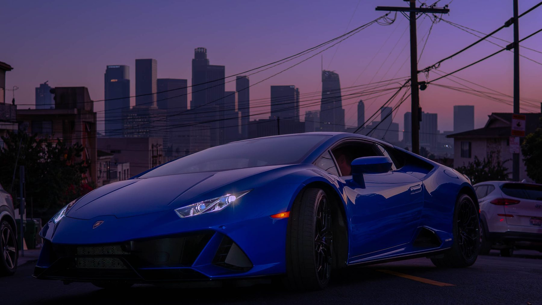 Blue Lamborghini with the Los Angeles skyline at dusk