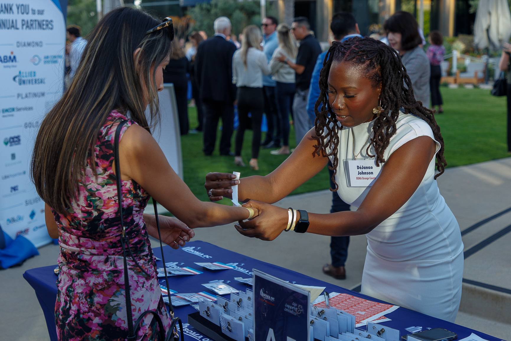 Two guests exchanging a card at the BOMA OC partner table