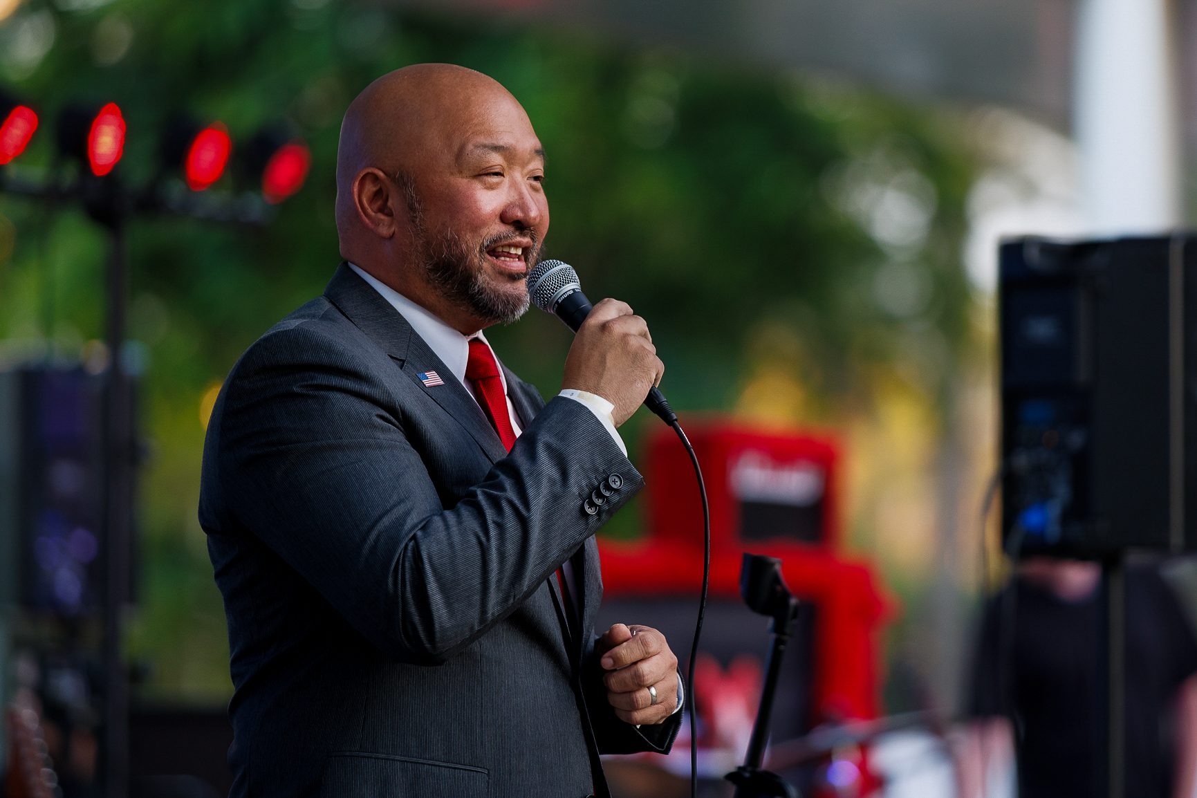 Speaker in a suit with a microphone beside the stage lights