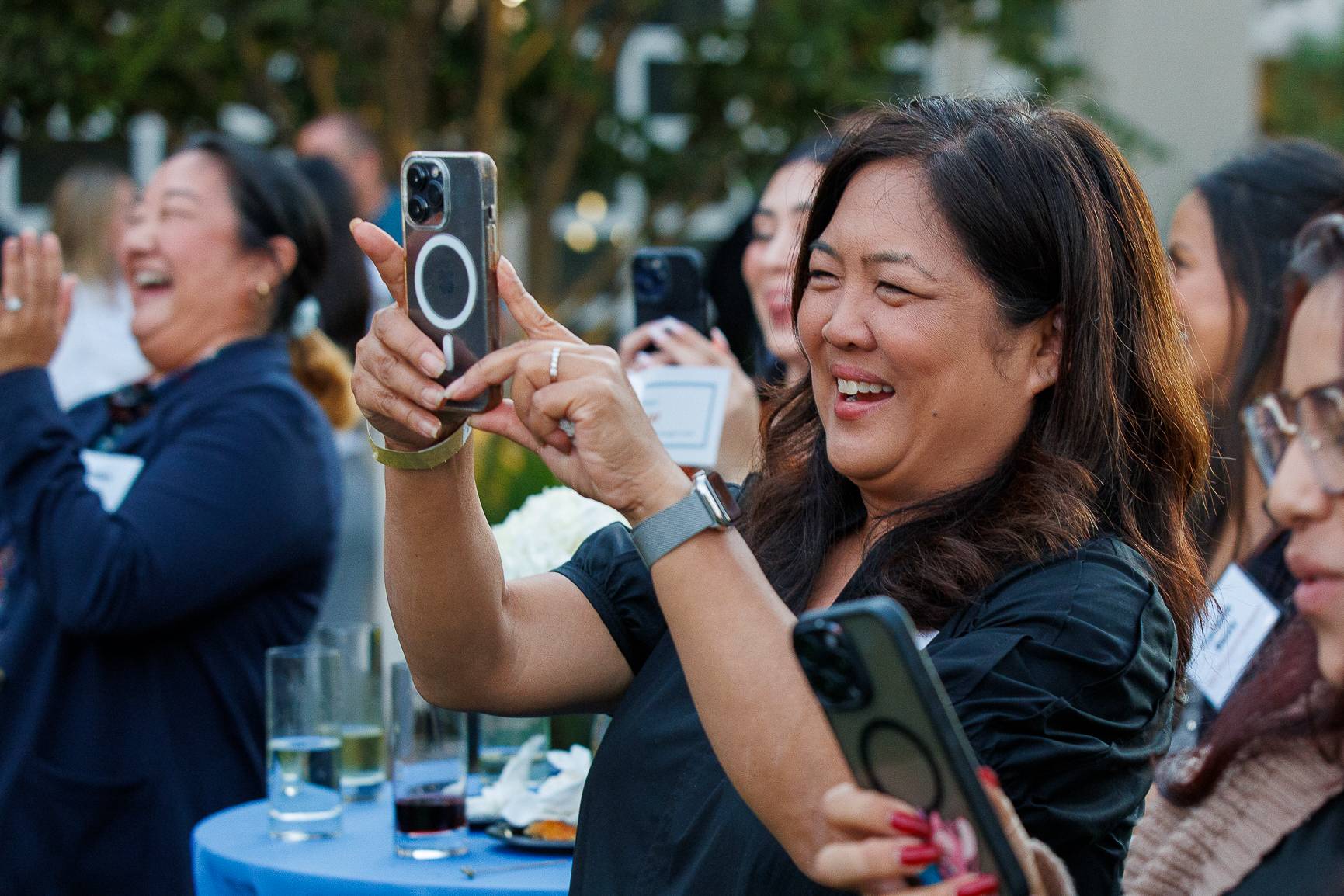 Guest smiling and taking a photo with her phone at the reception