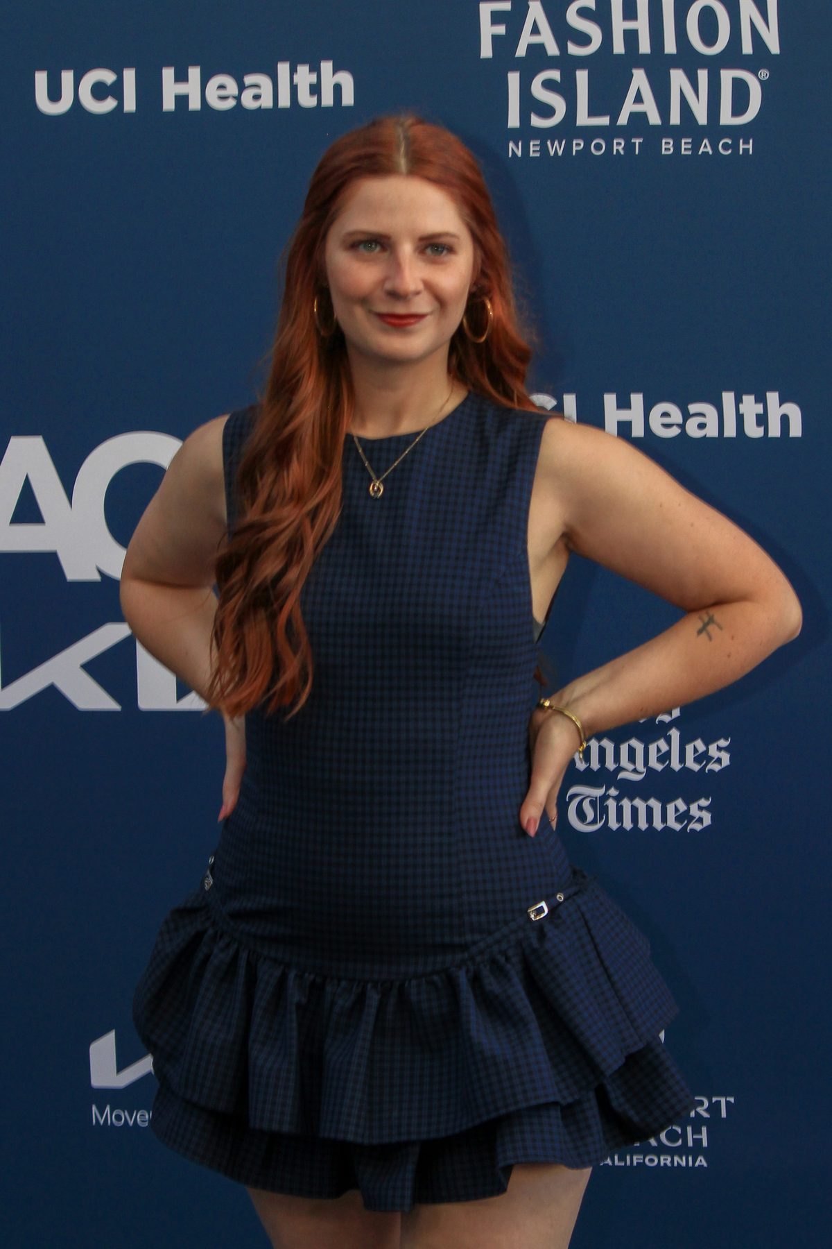 Woman in a navy dress posing at the Newport Beach Film Festival backdrop