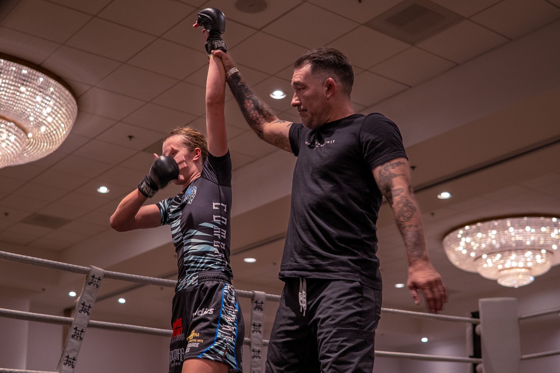 Fighter raising her glove as the referee watches