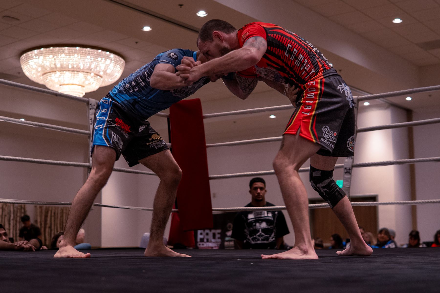 Two fighters locked up in a clinch inside the ring