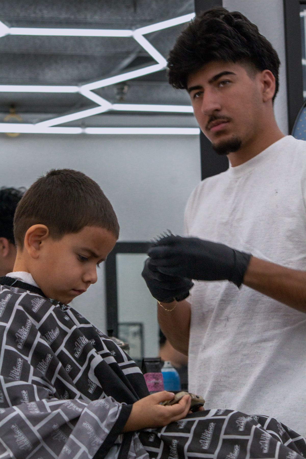 Barber trimming a young boy's hair in black and white