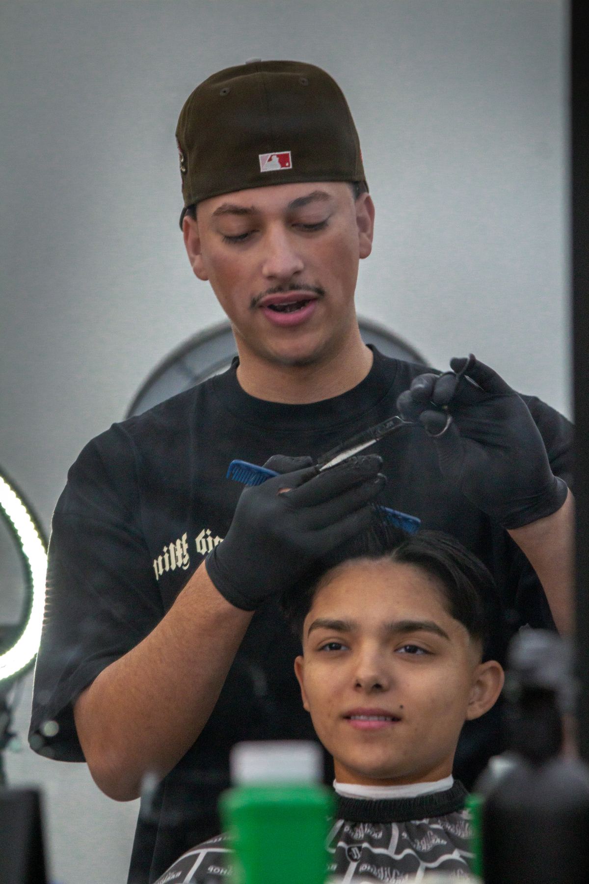 Barber styling a client's hair at The Vibe Barbershop