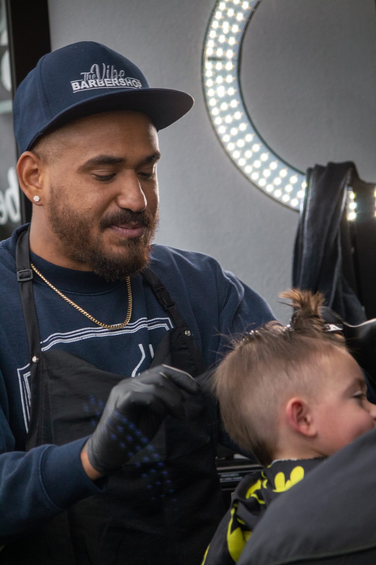 Barber in a cap giving a toddler a haircut