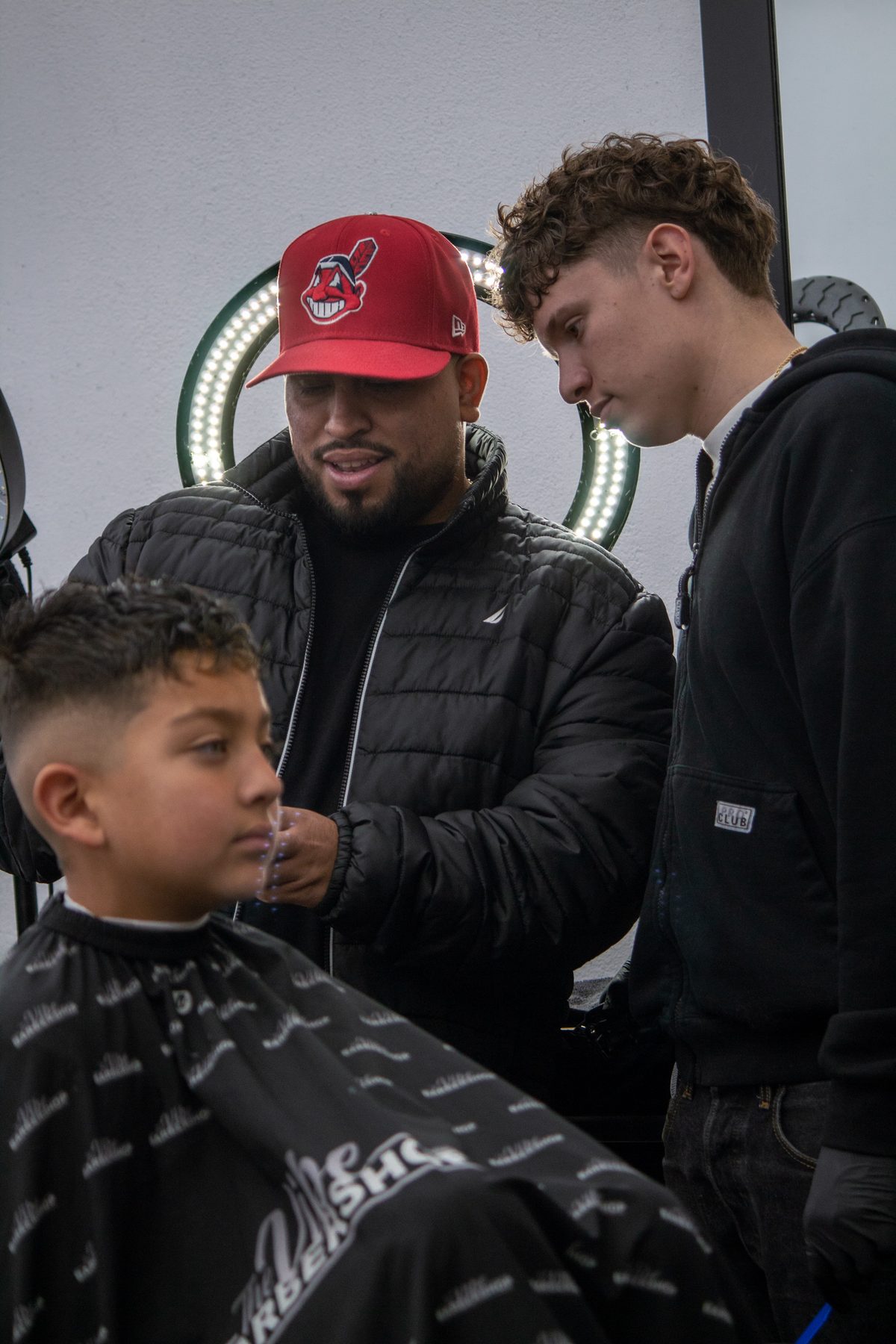 Barbers working together with a young client in the chair