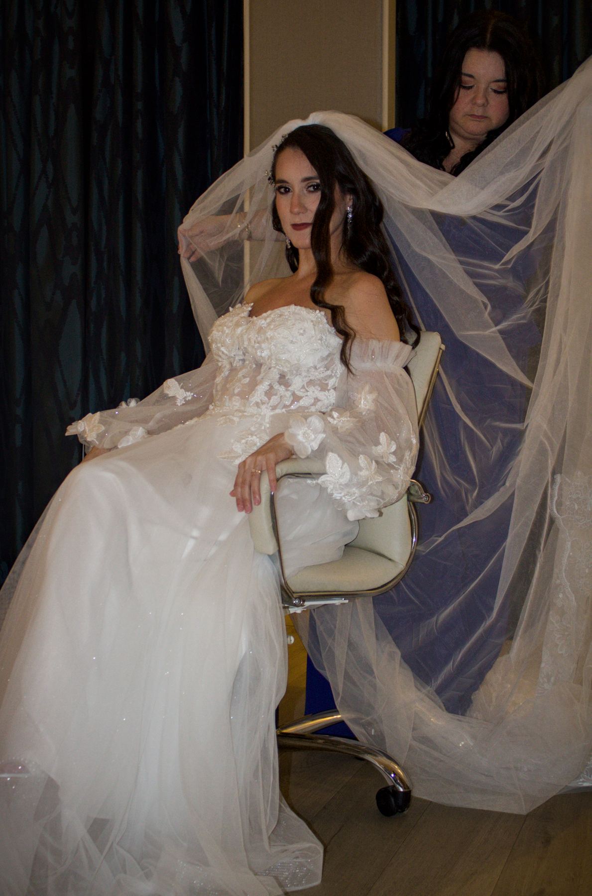 Bride in a veil seated by the window